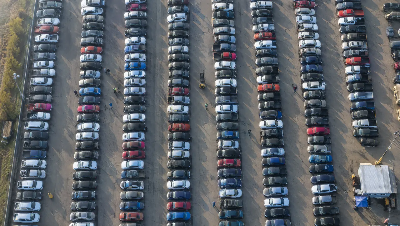 Aerial view of hundreds of cars parked in rows at an auction yard